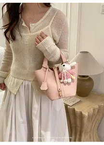 Elegant pink pebbled leather bucket bag featuring a cute white rabbit plush charm