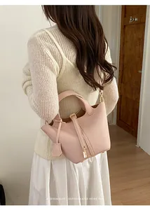 Elegant pink leather bucket bag carried by a model in a minimalist indoor setting.