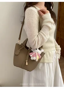 Sophisticated brown leather bucket bag with bear charm worn by a stylish female model