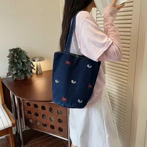 Vista dettagliata della borsa a secchiello in denim casual con ricami di cavalli.