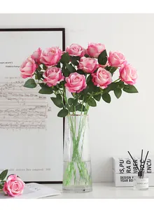 Nahaufnahme eines künstlichen rosa Rosenstrauchs in einer klaren Glasvase als Heimdekoration.