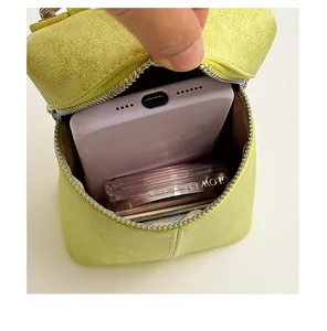 Detail view of green mini crossbody bag showing interior phone and makeup capacity