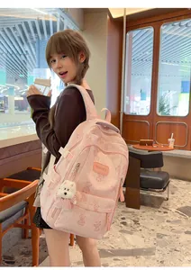 Lifestyle view of a cute pink backpack with bear patterns worn by a model in a cafe