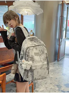 Girl wearing a grey tie-dye large capacity backpack with a white fuzzy bear keychain