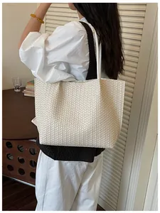Gros plan détaillé d'un élégant sac cabas tressé en cuir blanc porté sur l'épaule.