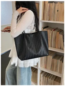 Vue détail du sac cabas épaule en cuir tissé noir mettant en valeur la texture élégante.