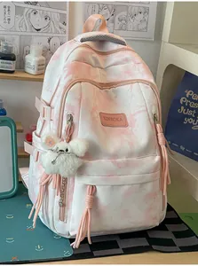 Detail view of a stylish pink tie-dye backpack featuring a fluffy white plush charm.