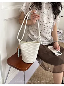 Detailed view of the elegant white woven bucket bag with beaded charm and stylish braided strap.