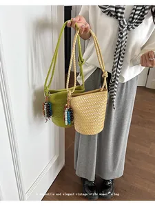 Detailed view of woven bucket bags in green and beige with beaded charms. Lifestyle detail shot.