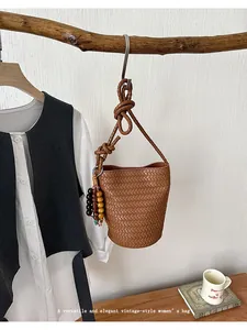 Chic brown woven bucket bag for women, vintage style shoulder bag with wooden beaded charm.