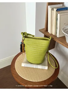 Green woven bucket bag, vintage style shoulder cross body bag with knot handle and charm.