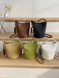 Stylish woven bucket bag with chic beaded charm, versatile crossbody design for women.