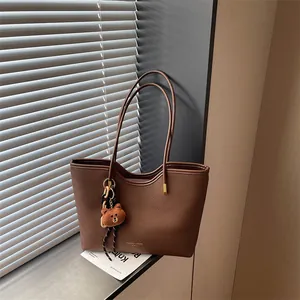 Brown PU leather tote bag for women, large capacity stylish shoulder bag with cute bear pendant.