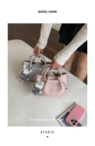 Model holding elegant pink and grey leather bucket handbags with cute bear charms