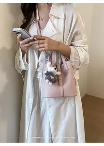 Close-up view of the minimalist pink leather bucket bag with cute plush rabbit charm detail.