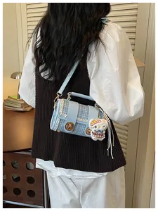 Detailed shot of trendy blue plaid shoulder bag with cute cartoon plush pendant, retro design.
