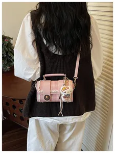 Chic pink tweed crossbody bag featuring a cute plush charm and stylish color block design.