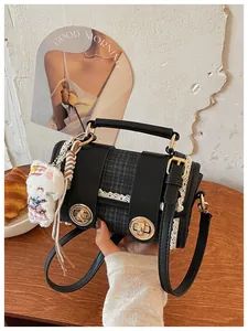 Detail shot of the black plaid chic shoulder bag with lace trim, metal locks, and cute plush pend.