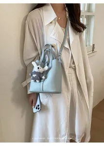 Light blue bucket bag detail with cute bunny plush charm, elegant style for summer.