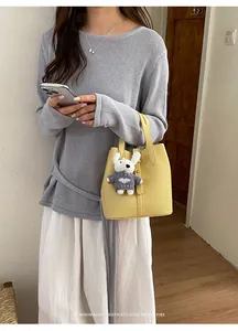 Sophisticated yellow textured bucket bag with a cute plush bear charm detail.