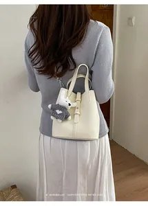 Elegant cream pebbled leather bucket bag for women with a cute grey rabbit charm detail