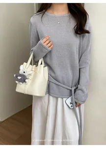 Close-up detail of the minimalist leather bucket bag with cute charm and stylish apparel.