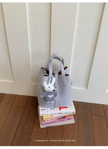 Detailed shot of a minimalist lavender bucket bag with a plush bear charm accessory.