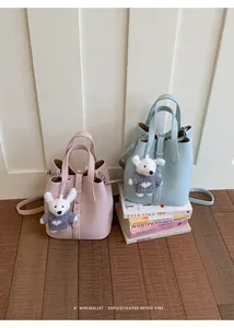 Detailed view of sophisticated leather bucket bags in pink and blue with bear charms