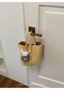 Stylish yellow bucket bag with cute plush charm hanging on a vintage door handle