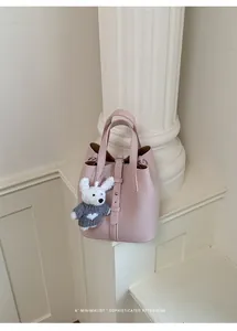 Detail view of stylish pink leather bucket bag with cute plush pendant and retro column.