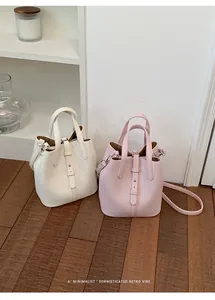 Detailed view of minimalist bucket bags in white and pink, featuring chic leather straps.