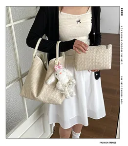 Vue détaillée du sac cabas beige tissé, de la pochette assortie et du joli charm lapin.