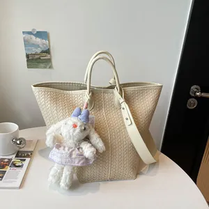 Vue détaillée de l'élégant sac cabas tressé en cuir beige avec bandoulière et charm en peluche.
