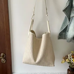 Vue détaillée du sac cabas tissé à l'épaule, design élégant blanc cassé, style quotidien.