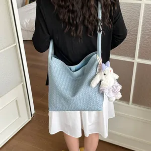 Sac cabas bandoulière en cuir tressé bleu clair avec joli pendentif lapin en peluche.