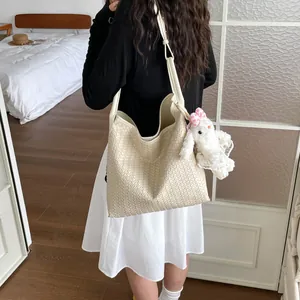 Vue détaillée du sac à épaule tissé tendance avec un charmant pendentif lapin en peluche.