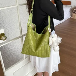 Gros plan détaillé du sac porté épaule vert tissé élégant dans une scène quotidienne.