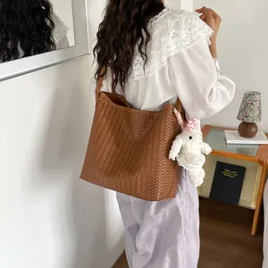 Élégant sac cabas porté épaule en cuir tressé marron pour femme, sac de ville chic.