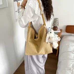 Vue détaillée du sac porté épaule tressé dans un décor de chambre avec joli charm.