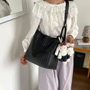 Vue détaillée du sac cabas d'épaule noir tressé élégant avec joli pendentif lapin mignon.