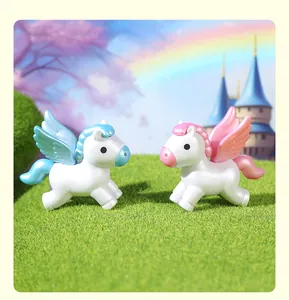 Close-up of pink and blue mini winged pegasus figurines on grass with a castle background.