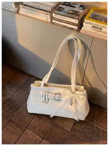 Gros plan sur le sac porté épaule blanc avec charm nœud en dentelle de perles et boucle élégante.