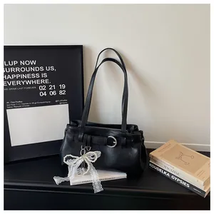 Détail de sac à épaule noir élégant avec nœud en dentelle de perles et boucle en métal.