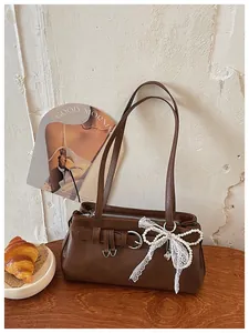 Détail d'un sac porté épaule marron vintage avec nœud en perles de dentelle et boucle élégante.