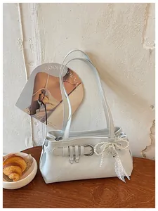 Vue rapprochée détaillée du sac porté épaule aisselle bleu clair avec boucle métallique et nœud perlé.