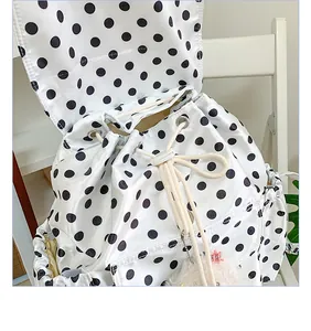 Close-up detail of stylish black and white polka dot drawstring backpack with flap.