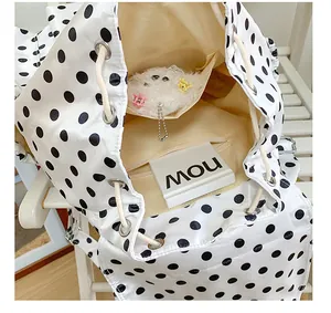 Detail view of stylish white black polka dot backpack, showing interior storage design.