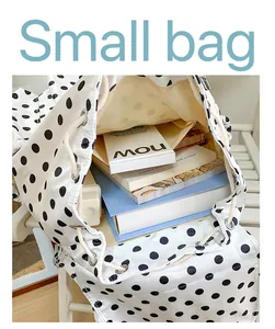 Close detail view of the stylish white polka dot drawstring backpack open with books inside.