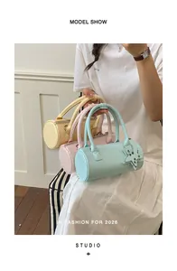 Close-up of pastel woven cylinder handbags held by a model in a stylish studio setting