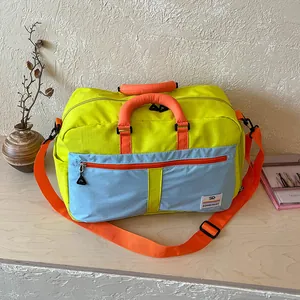 Color-block travel duffel bag, detailed view showing front zipper pocket and handle.